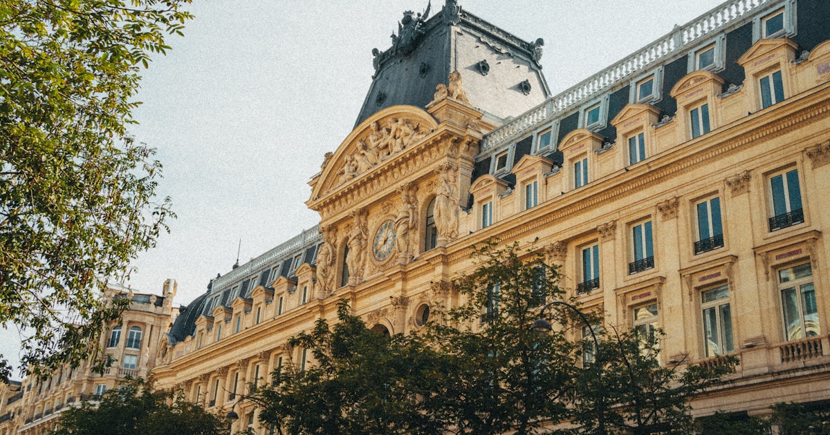 Façade en pierre d'un grand bâtiment institutionnel parisien surmonté d'une horloge