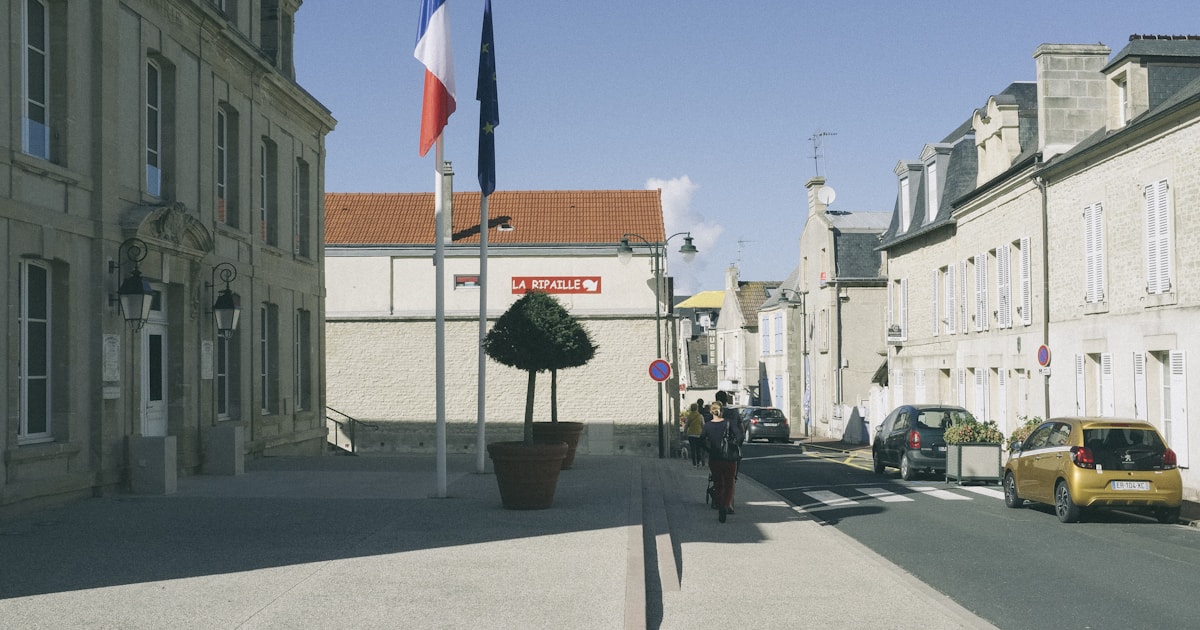 Rue d'un bourg français bordée par la mairie et ses drapeaux, un matin de rentrée